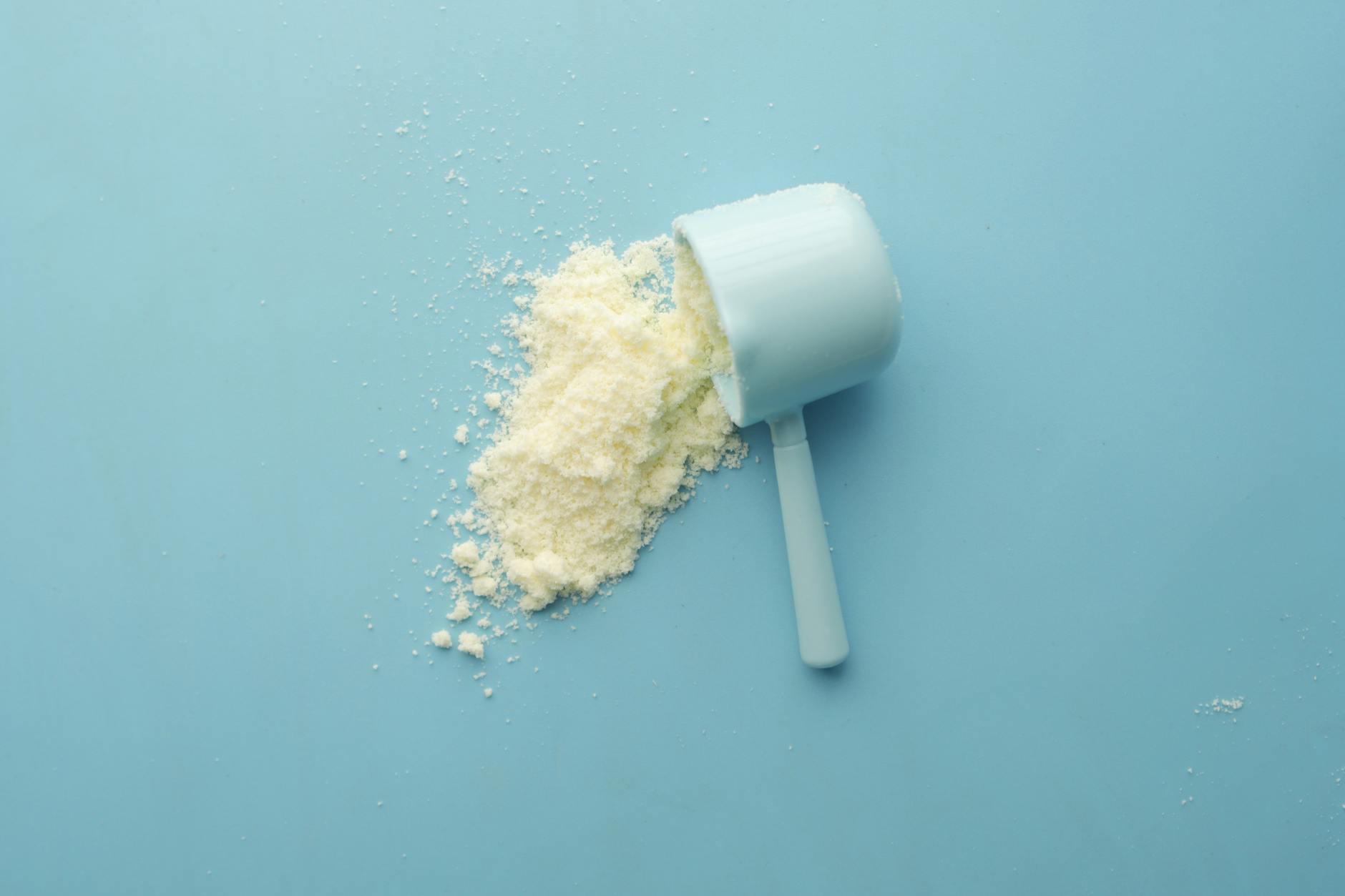 photo of a white powder and a scoop lying on the blue background